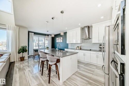 Kitchen featuring a kitchen breakfast bar, a center island with sink, white cabinetry, pendant lighting, and modern cabinets - 3716 46 Avenue, Beaumont, AB - Indoor Photo Showing Kitchen With Upgraded Kitchen