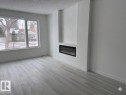 Living area featuring light-toned flooring, a large window, a modern linear fireplace, and clean white walls - 3605 112 Ave, Edmonton, AB  - Indoor Photo Showing Living Room With Fireplace 
