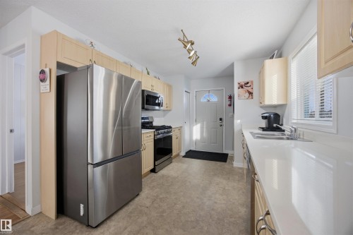 Kitchen featuring stainless steel appliances, light wood finish cabinetry, light countertops, track lighting, and light flooring - 2340 30 Avenue, Edmonton, AB - Indoor Photo Showing Kitchen With Double Sink