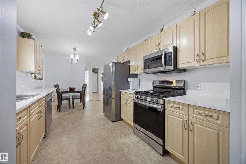 Kitchen with stainless steel appliances, light countertops, light wood finish cabinetry, light floors, and a textured ceiling - 2340 30 Avenue, Edmonton, AB - Indoor Photo Showing Kitchen