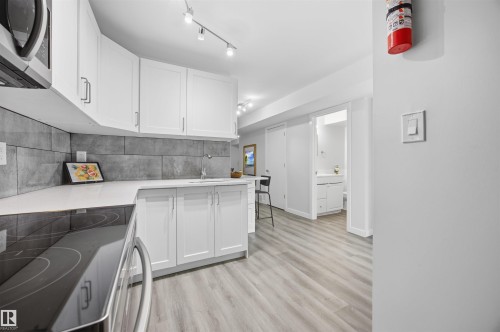Kitchen with range with electric stovetop, white cabinetry, stainless steel microwave, and light wood-type flooring - 2340 30 Avenue, Edmonton, AB - Indoor Photo Showing Kitchen