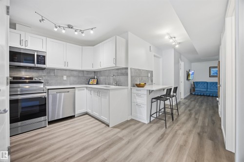 Kitchen featuring stainless steel appliances, white cabinets, rail lighting, light wood finished floors, and tasteful backsplash - 2340 30 Avenue, Edmonton, AB - Indoor Photo Showing Kitchen