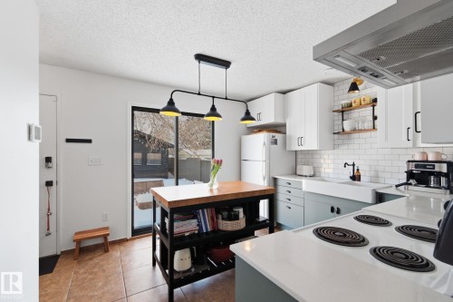 Kitchen featuring exhaust hood, light countertops, open shelves, a textured ceiling, and white appliances - 18717 57 Avenue, Edmonton, AB - Indoor Photo Showing Kitchen