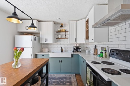 Kitchen featuring two tone cabinets, electric stove, open shelves, hanging light fixtures, and freestanding refrigerator - 18717 57 Avenue, Edmonton, AB - Indoor Photo Showing Kitchen
