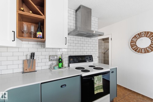 Kitchen featuring electric stove, open shelves, dark tile patterned floors, tasteful backsplash, and a textured ceiling - 18717 57 Avenue, Edmonton, AB - Indoor Photo Showing Kitchen