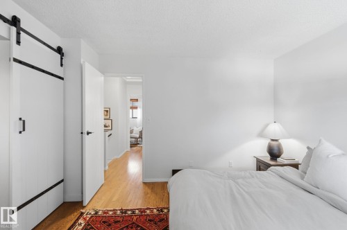 Bedroom featuring a barn door, light wood-style floors, and a textured ceiling - 18717 57 Avenue, Edmonton, AB - Indoor Photo Showing Bedroom