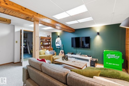 Carpeted living room with a paneled ceiling and beamed ceiling - 18717 57 Avenue, Edmonton, AB - Indoor Photo Showing Basement