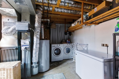 Laundry area featuring concrete flooring, water heater, separate washer and dryer, and heating unit - 18717 57 Avenue, Edmonton, AB - Indoor Photo Showing Laundry Room