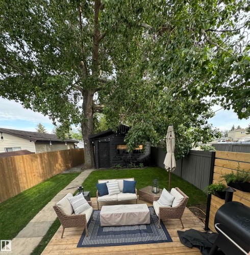 Fenced backyard featuring an outdoor lounge area, a wooden deck, grilling area, and an outdoor structure - 18717 57 Avenue, Edmonton, AB - Outdoor With Deck Patio Veranda With Backyard