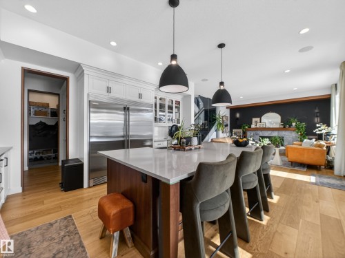 Two tone kitchen with built in refrigerator, two tone color scheme, a breakfast bar area, pendant lighting, and light wood finished floors - 5507 Chegwin Point(E), Edmonton, AB - Indoor Photo Showing Kitchen With Upgraded Kitchen