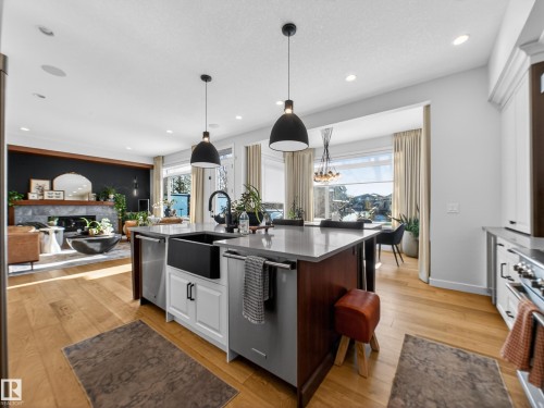 Kitchen featuring hanging light fixtures, light wood-style floors, stainless steel appliances, white cabinets, and an island with sink - 5507 Chegwin Point(E), Edmonton, AB - Indoor Photo Showing Kitchen With Upgraded Kitchen