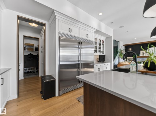 Dual tone kitchen with built in refrigerator, glass fronted cabinets, light wood-style flooring, two tone cabinetry, and light stone countertops - 5507 Chegwin Point(E), Edmonton, AB - Indoor Photo Showing Kitchen With Upgraded Kitchen