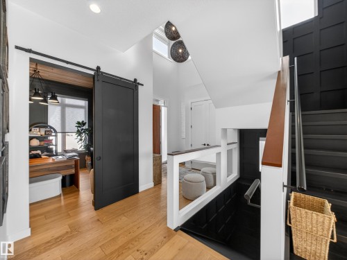Interior space with healthy amount of natural light, wood finished floors, a barn door, and a high ceiling - 5507 Chegwin Point(E), Edmonton, AB - Indoor Photo Showing Other Room