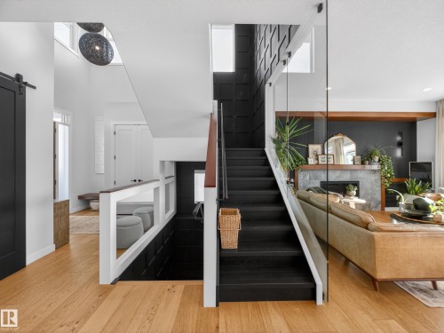Stairs featuring a barn door, a multi sided fireplace, and wood finished floors - 5507 Chegwin Point(E), Edmonton, AB - Indoor Photo Showing Other Room