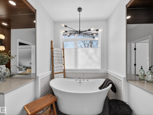 Bathroom featuring a wainscoted wall, a soaking tub, and a chandelier - 5507 Chegwin Point(E), Edmonton, AB - Indoor Photo Showing Bathroom