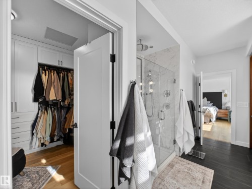 Bathroom with a spacious closet, ensuite bath, a marble finish shower, and dark wood-type flooring - 5507 Chegwin Point(E), Edmonton, AB - Indoor