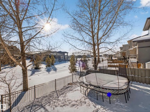 Snow covered patio with a trampoline, a fenced backyard, and a residential view - 5507 Chegwin Point(E), Edmonton, AB - Outdoor