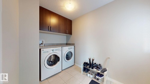 Laundry area featuring cabinet space, a textured ceiling, light tile patterned floors, and washer and clothes dryer - 1275 Chappelle Boulevard Sw, Edmonton, AB - Indoor Photo Showing Laundry Room