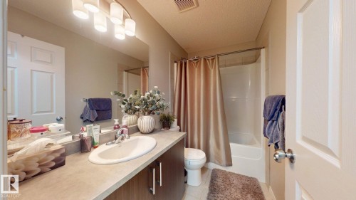 Full bathroom with vanity, a textured ceiling, shower / bathtub combination with curtain, and light tile patterned flooring - 1275 Chappelle Boulevard Sw, Edmonton, AB - Indoor Photo Showing Bathroom