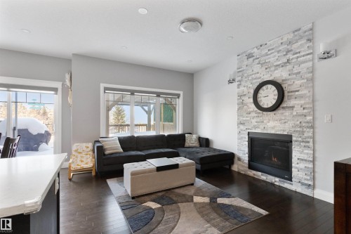 Living room featuring dark wood-style floors and a stone fireplace - 56 Durrand Bend, Fort Saskatchewan, AB - Indoor Photo Showing Living Room With Fireplace