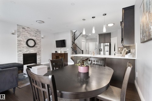 Dining room featuring a stone fireplace and dark wood-style flooring - 56 Durrand Bend, Fort Saskatchewan, AB - Indoor Photo Showing Dining Room