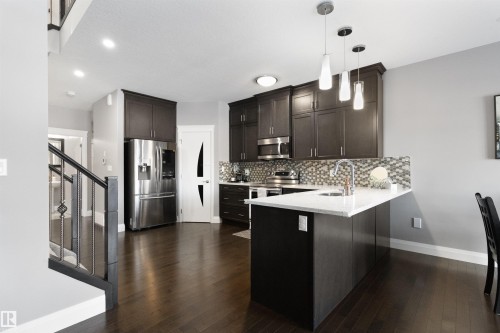 Kitchen featuring stainless steel appliances, a peninsula, dark wood finish cabinets, and pendant lighting - 56 Durrand Bend, Fort Saskatchewan, AB - Indoor Photo Showing Kitchen With Upgraded Kitchen