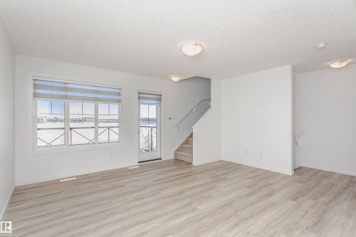 Unfurnished living room with a textured ceiling and light wood-style flooring - 2412 192 Street, Edmonton, AB - Indoor Photo Showing Other Room