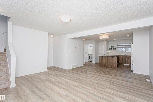 Unfurnished living room featuring independent washer and dryer, light wood-type flooring, and a textured ceiling - 2412 192 Street, Edmonton, AB - Indoor