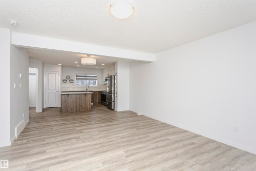 Kitchen with open floor plan, a kitchen island, light wood-type flooring, freestanding refrigerator, and a textured ceiling - 2412 192 Street, Edmonton, AB - Indoor Photo Showing Other Room