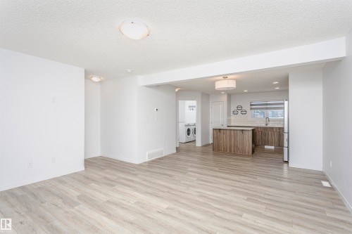 Unfurnished living room featuring independent washer and dryer, light wood-style floors, a textured ceiling, and recessed lighting - 2412 192 Street, Edmonton, AB - Indoor Photo Showing Other Room