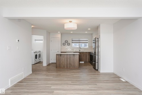 Kitchen featuring a kitchen island, light countertops, light wood-type flooring, and wood finish cabinets - 2412 192 Street, Edmonton, AB - Indoor