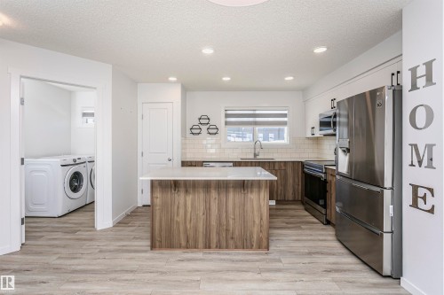 Kitchen with stainless steel appliances, a center island, two tone cabinetry, backsplash, and a textured ceiling - 2412 192 Street, Edmonton, AB - Indoor Photo Showing Other Room