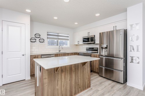 Kitchen featuring stainless steel appliances, dual tone cabinetry, a center island, tasteful backsplash, and light stone countertops - 2412 192 Street, Edmonton, AB - Indoor Photo Showing Kitchen With Stainless Steel Kitchen With Upgraded Kitchen