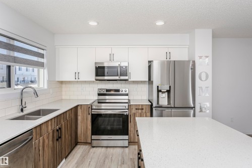 Kitchen with two tone cabinets, stainless steel appliances, light stone countertops, light wood finished floors, and decorative backsplash - 2412 192 Street, Edmonton, AB - Indoor Photo Showing Kitchen With Stainless Steel Kitchen With Double Sink With Upgraded Kitchen