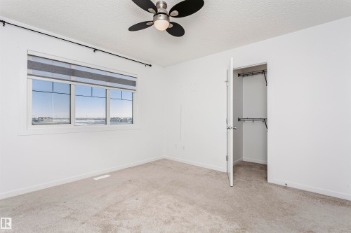 Unfurnished bedroom featuring a spacious closet, a textured ceiling, light carpet, and a ceiling fan - 2412 192 Street, Edmonton, AB - Indoor Photo Showing Other Room
