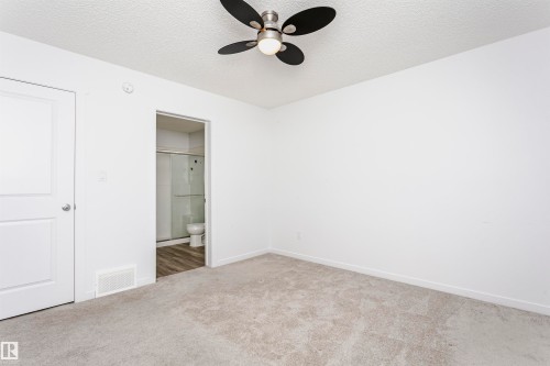 Unfurnished bedroom with a textured ceiling, carpet floors, ensuite bath, and a ceiling fan - 2412 192 Street, Edmonton, AB - Indoor Photo Showing Other Room