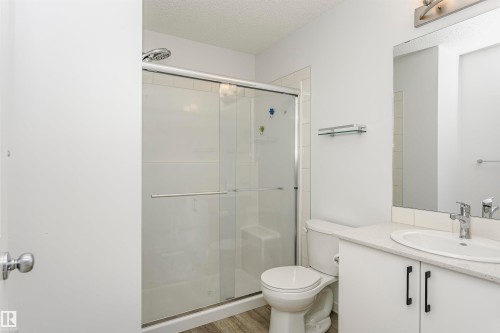Bathroom featuring vanity, a textured ceiling, a stall shower, and light wood-style floors - 2412 192 Street, Edmonton, AB - Indoor Photo Showing Bathroom