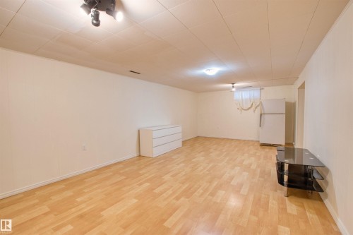 Finished below grade area featuring freestanding refrigerator and light wood-style floors - 9907 165 Street, Edmonton, AB - Indoor Photo Showing Other Room