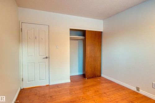 Unfurnished bedroom featuring light wood finished floors, a textured ceiling, and a closet - 9907 165 Street, Edmonton, AB - Indoor Photo Showing Other Room