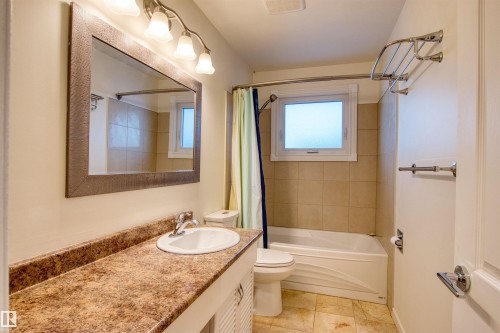 Bathroom featuring vanity, shower / bath combination with curtain, and light tile patterned floors - 9907 165 Street, Edmonton, AB - Indoor Photo Showing Bathroom
