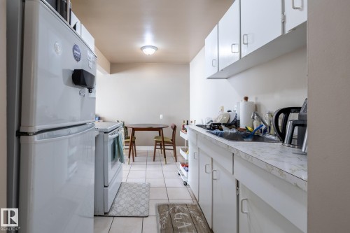 Kitchen featuring white cabinetry, fridge, light countertops, white electric range, and light tile patterned flooring - 15 10620 122 Street, Edmonton, AB - Indoor