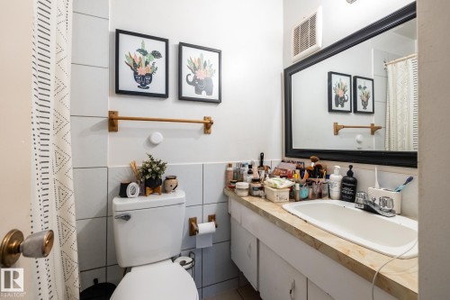 Full bath featuring a shower with curtain, vanity, and tile walls - 15 10620 122 Street, Edmonton, AB - Indoor Photo Showing Bathroom