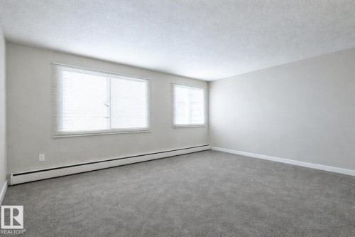 Unfurnished room with baseboard heating, a textured ceiling, and carpet flooring - 15 10620 122 Street, Edmonton, AB - Indoor Photo Showing Other Room
