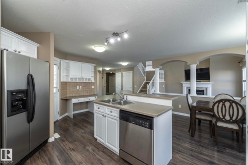 Kitchen with stainless steel appliances, arched walkways, white cabinetry, a kitchen island with sink, and open shelves - 16454 61A Street, Edmonton, AB - Indoor Photo Showing Kitchen With Double Sink