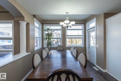 Dining area with a textured ceiling, hanging lights, dark wood-style flooring, and arched walkways - 16454 61A Street, Edmonton, AB - Indoor Photo Showing Dining Room