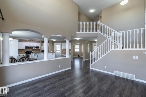 Unfurnished living room featuring arched walkways, ornate columns, a high ceiling, and dark wood finished floors - 16454 61A Street, Edmonton, AB - Indoor Photo Showing Other Room
