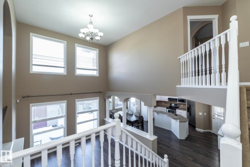 Staircase featuring a high ceiling, suspended lighting, wood finished floors, and arched walkways - 16454 61A Street, Edmonton, AB - Indoor Photo Showing Other Room