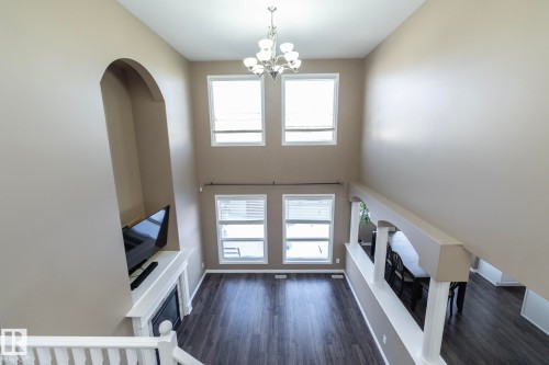 Unfurnished living room with a chandelier, a high ceiling, arched walkways, and dark wood-style flooring - 16454 61A Street, Edmonton, AB - Indoor Photo Showing Other Room