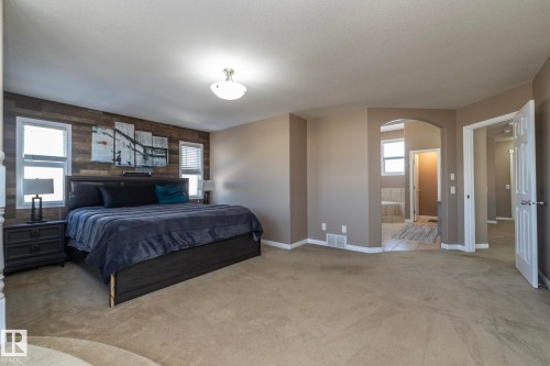 Bedroom featuring wooden walls, light colored carpet, arched walkways, ensuite bathroom, and an accent wall - 16454 61A Street, Edmonton, AB - Indoor Photo Showing Bedroom
