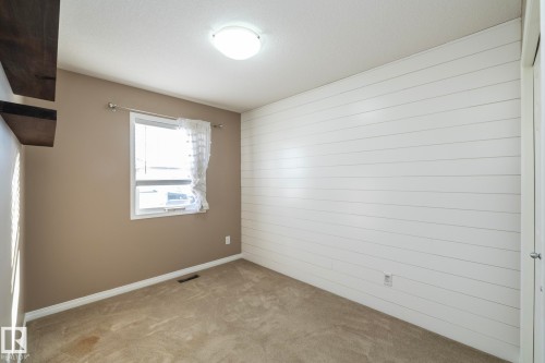 Empty room with light colored carpet and wood walls - 16454 61A Street, Edmonton, AB - Indoor Photo Showing Other Room